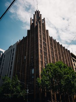 A magnificent Art Deco skyscraper under a clear blue sky with lush trees at its base.. pexels, magnificent, deco