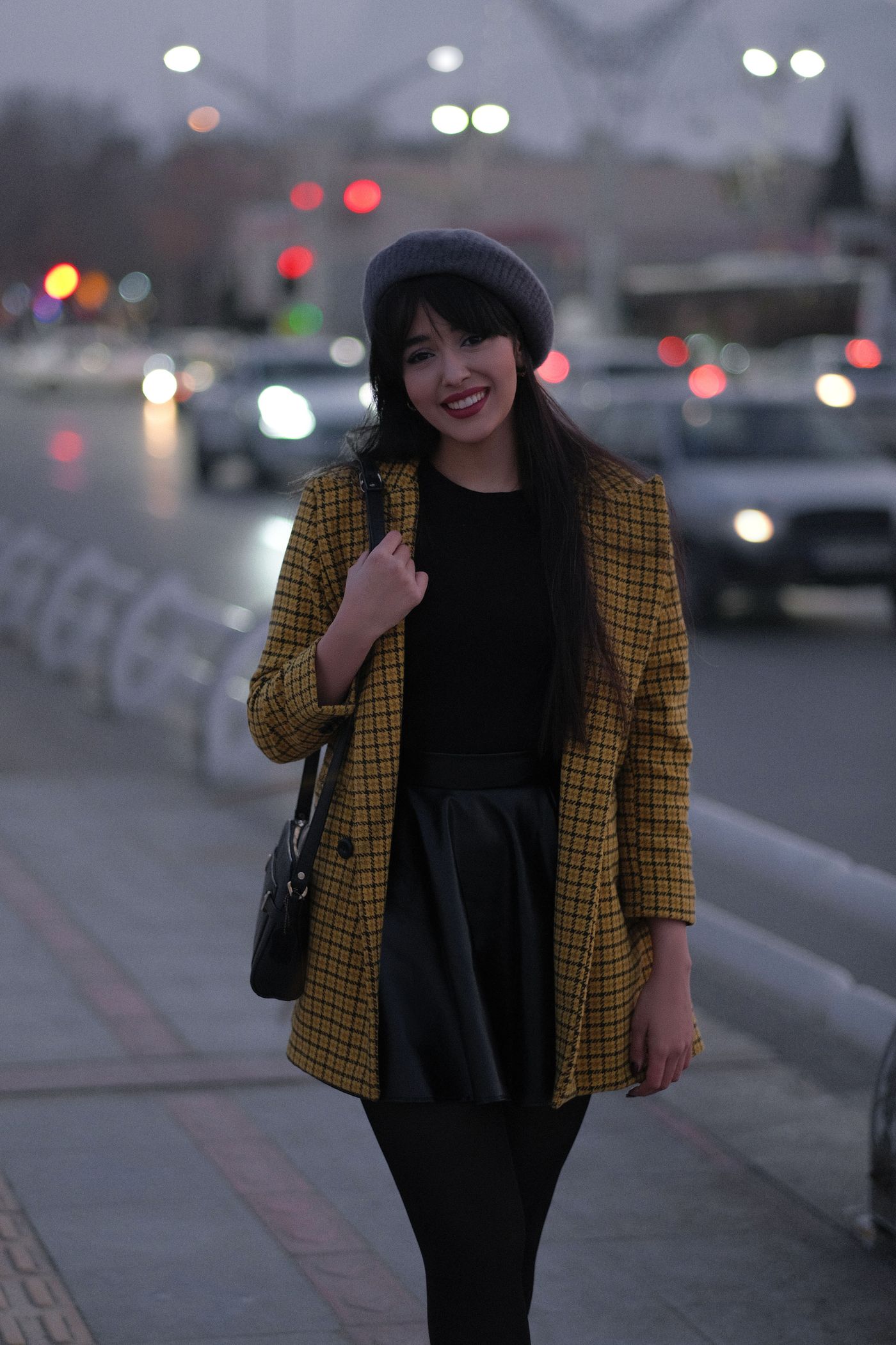 Woman in a plaid blazer and beret on an evening street