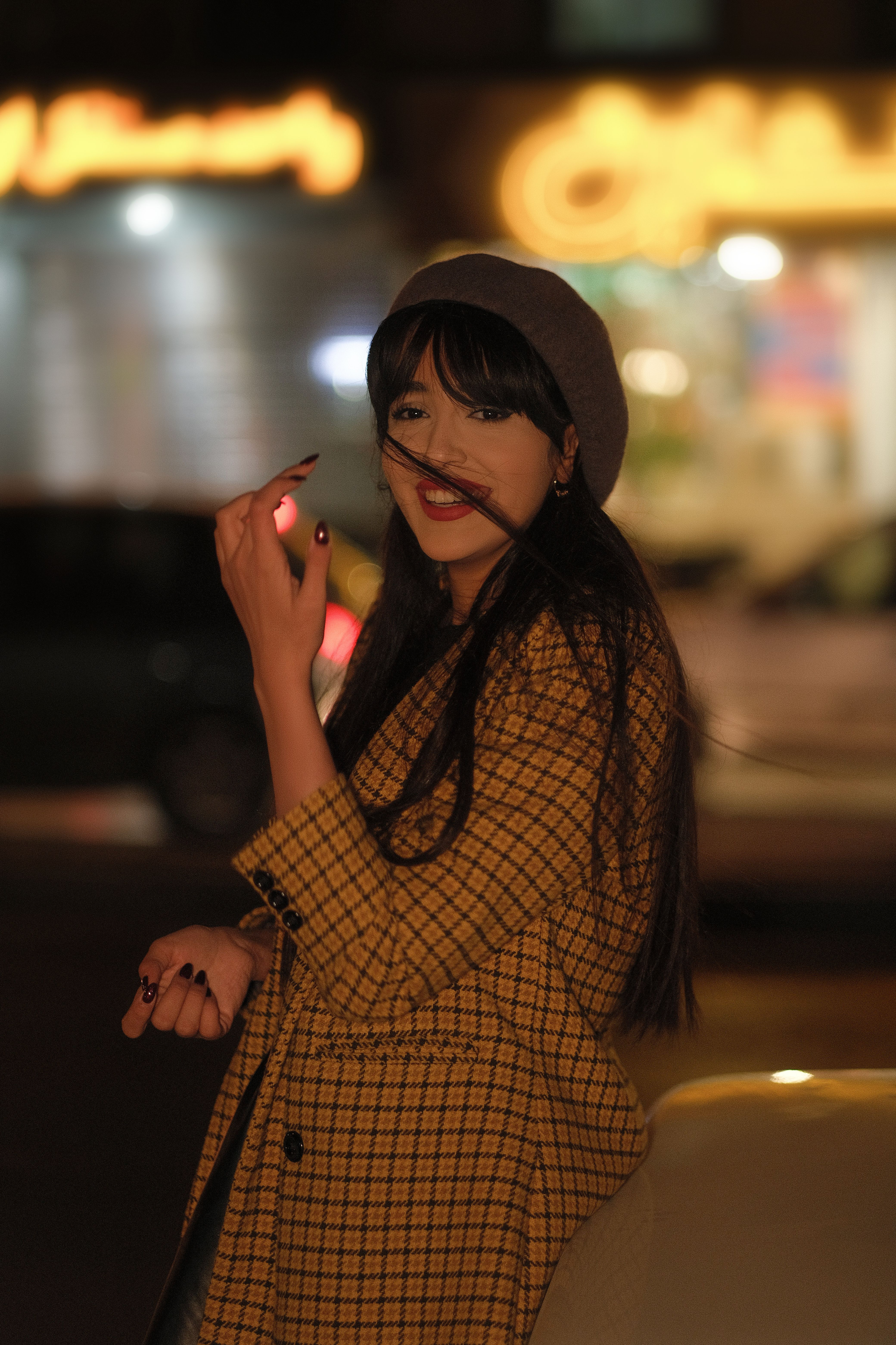 Stylish woman in a checkered coat enjoying a city evening atmosphere.