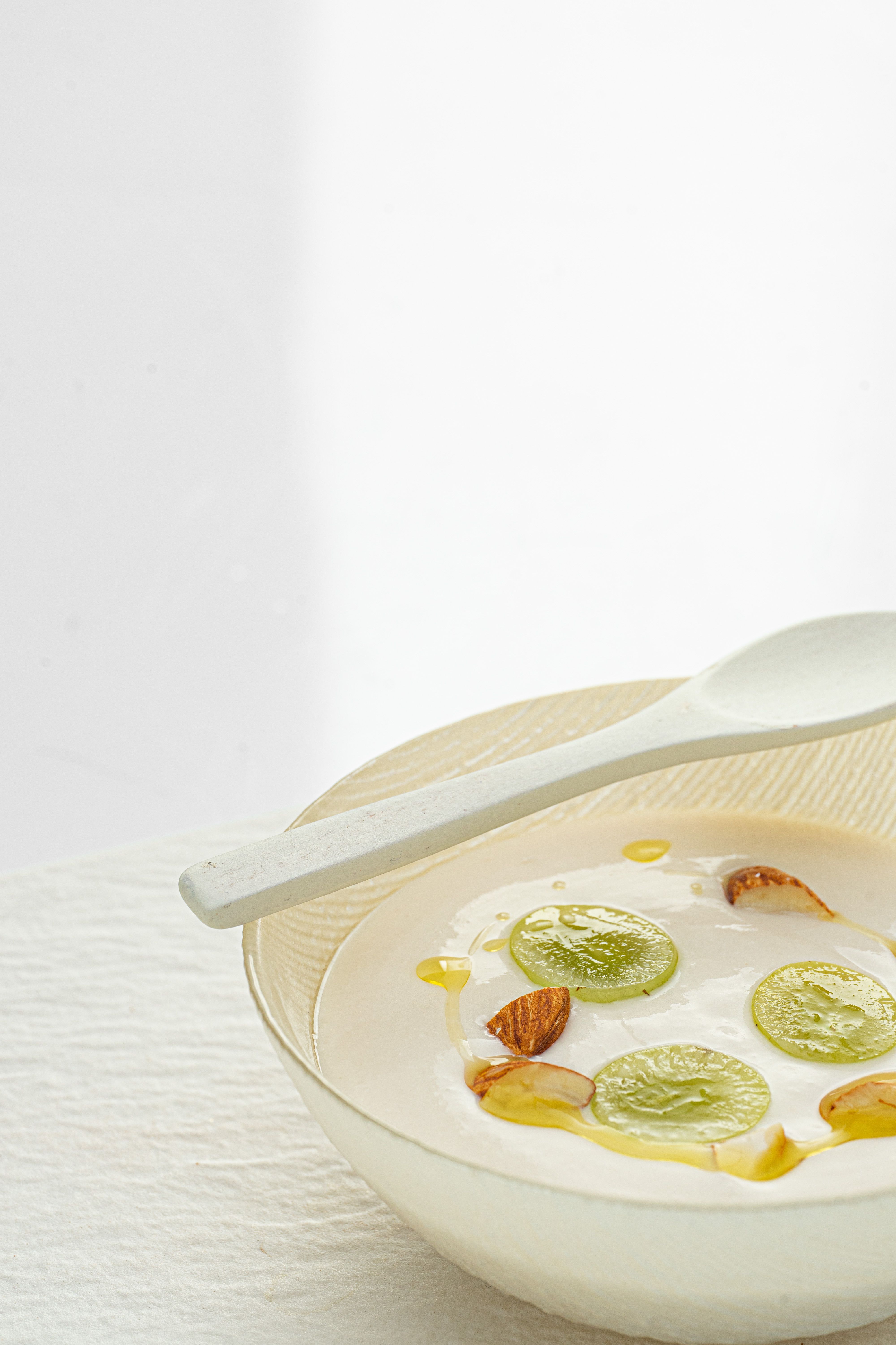 A close-up of a refreshing bowl of yogurt topped with grapes and almonds on a white background.