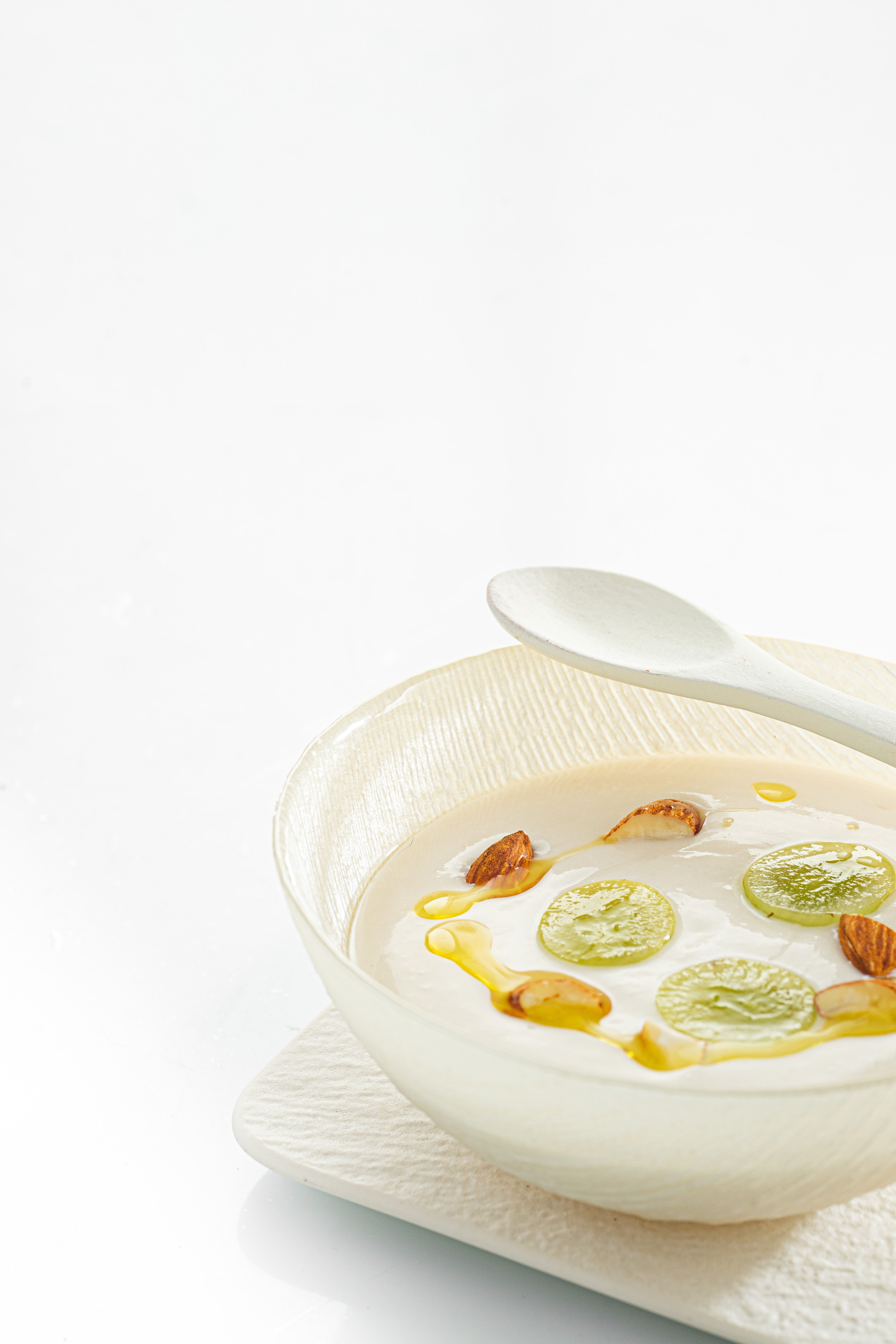Minimalist dessert dish with grapes, almonds, and cream on a white background, capturing a refined culinary presentation.