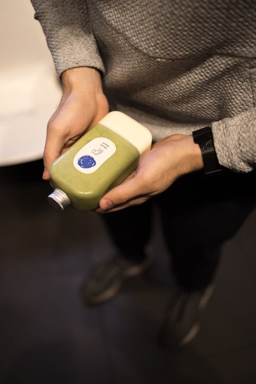 Free A person holding a green bottle in their hand Stock Photo