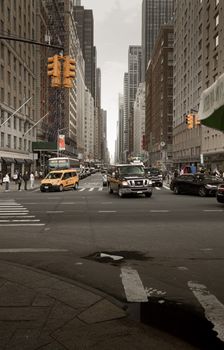 A bustling New York City street with taxis and cars amidst tall buildings.