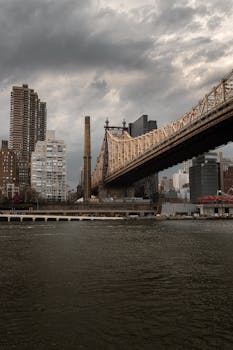Scenic view of Queensboro Bridge against Manhattan's dramatic skyline, reflecting New York City's architectural charm.
