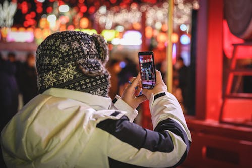 Person Wearing Jacket Taking Photo with a Smartphone