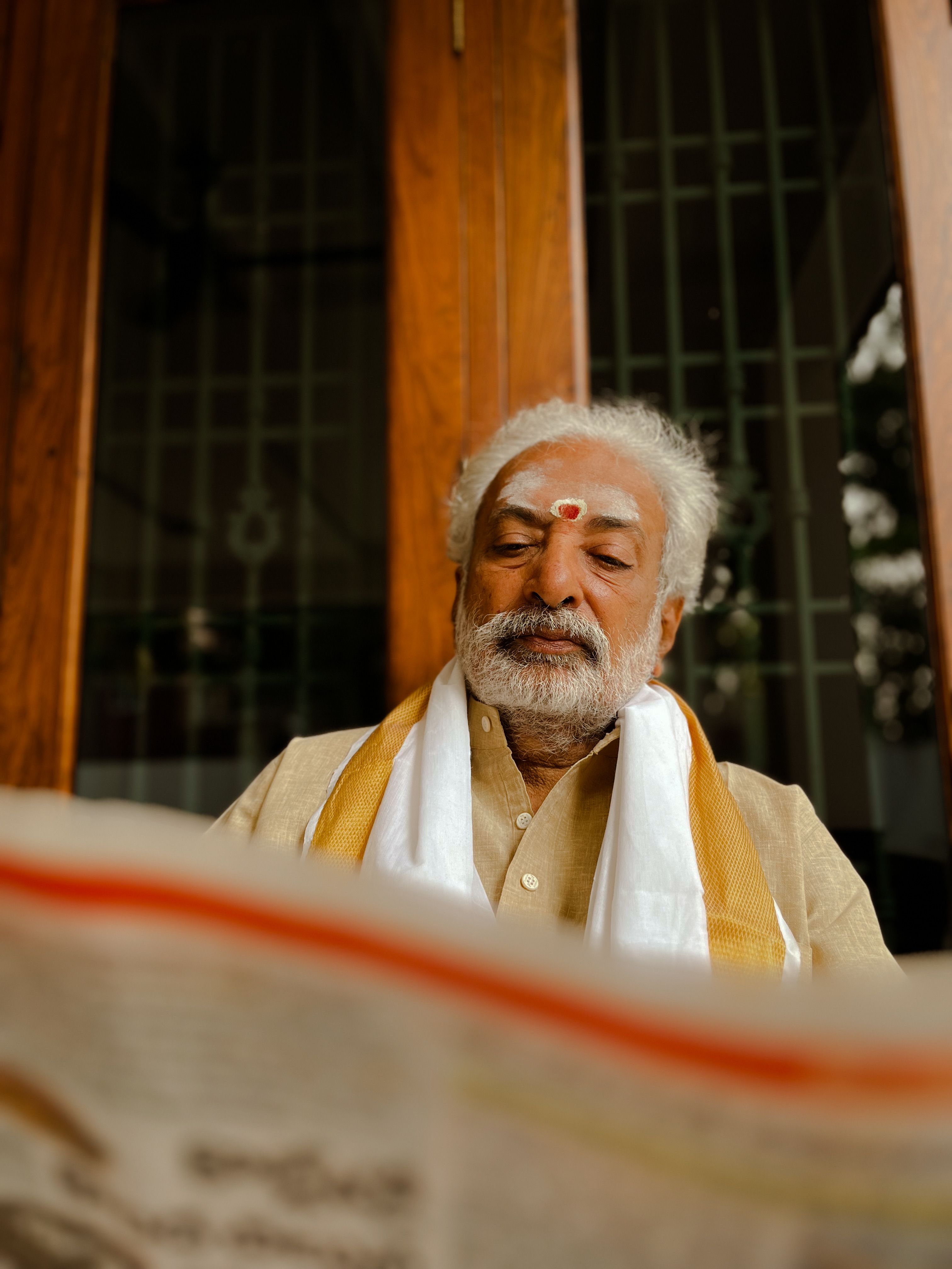 Senior Indian man with traditional clothing reading a newspaper, showcasing culture and wisdom.
