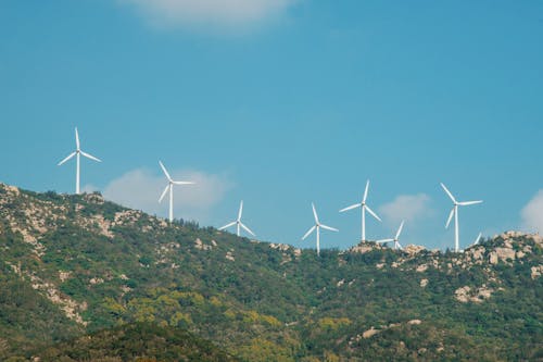 Бесплатное стоковое фото с ветрогенераторы, голубое небо, зеленая гора