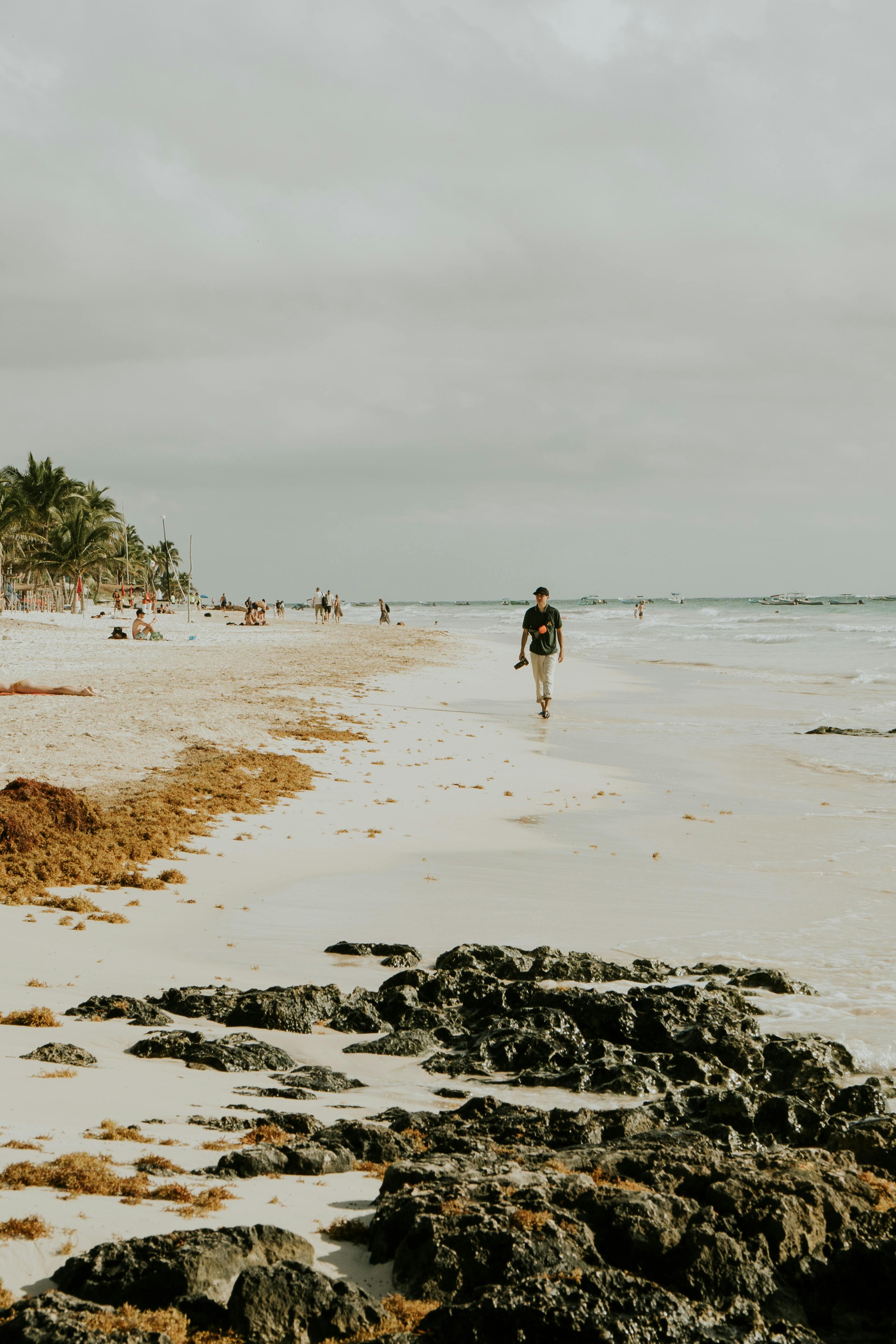 A tranquil view of a sandy beach with rocky shorelines and people enjoying the outdoors.