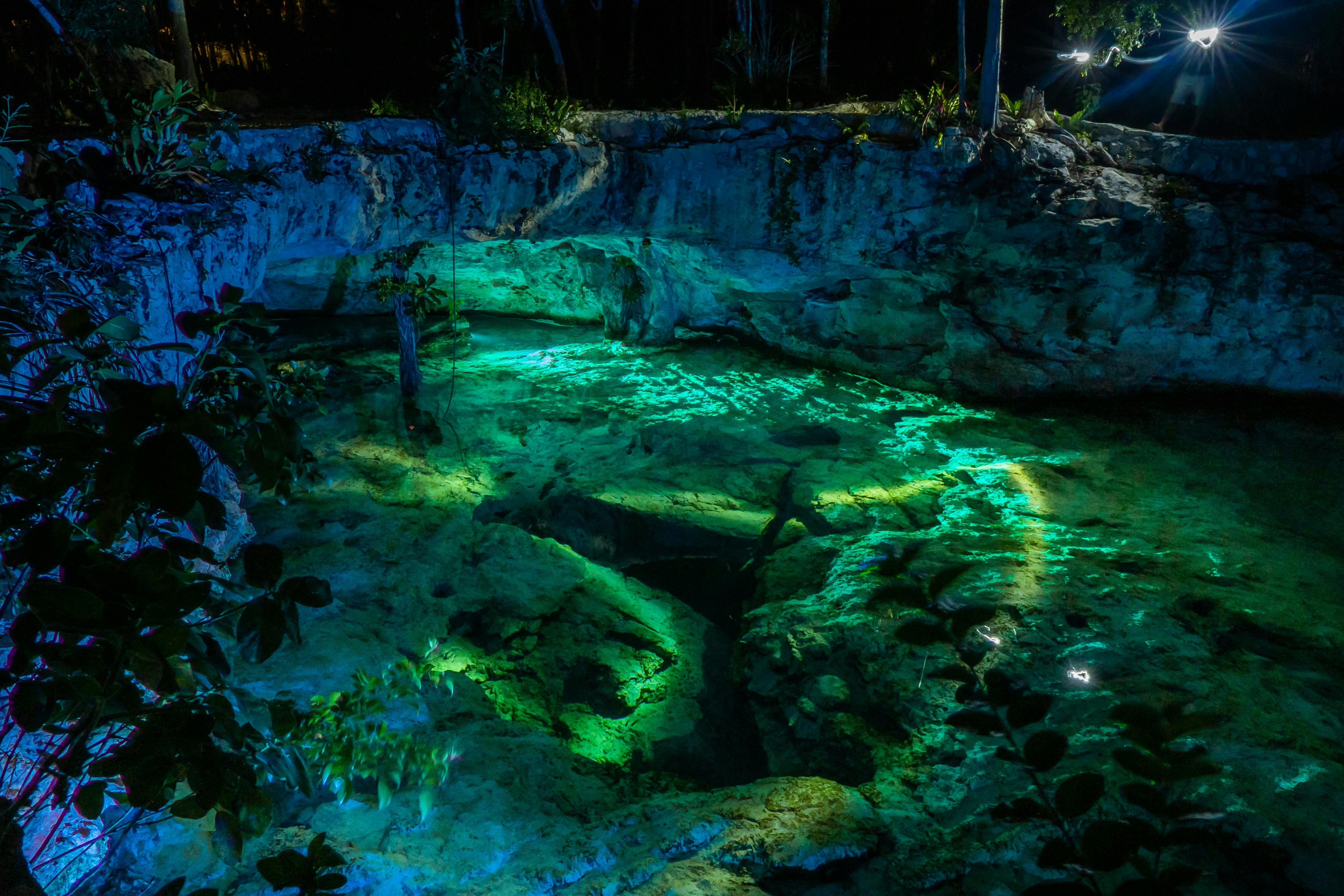 underwater caves riviera maya cenotes - Vibrant night view of Grand Cenote in Tulum, Mexico, highlighting illuminated turquoise waters and rocky surroundings.