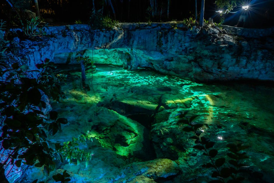 underwater caves riviera maya cenotes - Vibrant night view of Grand Cenote in Tulum, Mexico, highlighting illuminated turquoise waters and rocky surroundings.