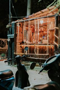 Illuminated outdoor bar with scooters parked nearby, creating a warm night atmosphere.