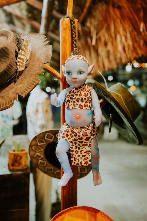 A Doll and Hats Hanging on a Wooden Stand 