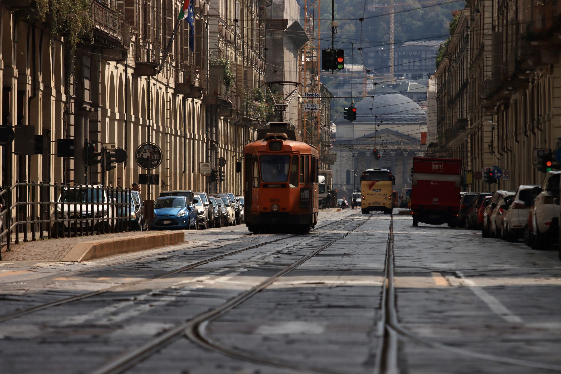 A vintage tram travels through a historic European street lined with classic buildings.