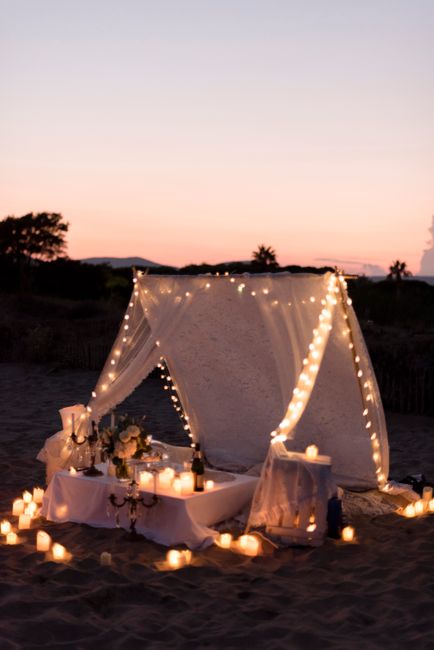 Enchanting beach setup with a candlelit tent and romantic ambiance at sunset.