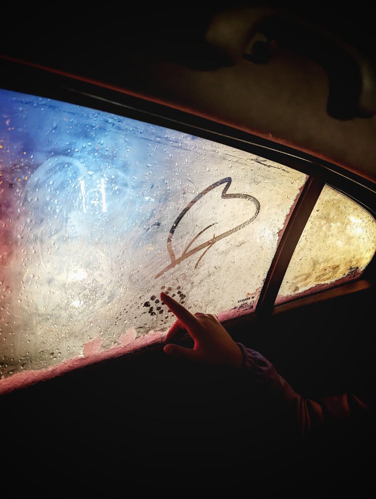 Hand Drawing A Heart On The Steamy Car Window 