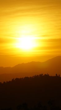 Golden sunset casting dramatic silhouettes over hills in Madanapalle, Andhra Pradesh, India.