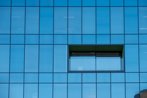 Free Close-up of a modern glass building facade with a distinctive window design. Stock Photo
