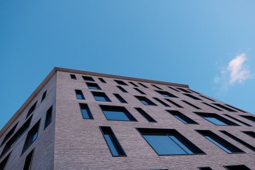 Free Low-angle view of a modern urban building against a clear blue sky, showcasing unique architecture. Stock Photo