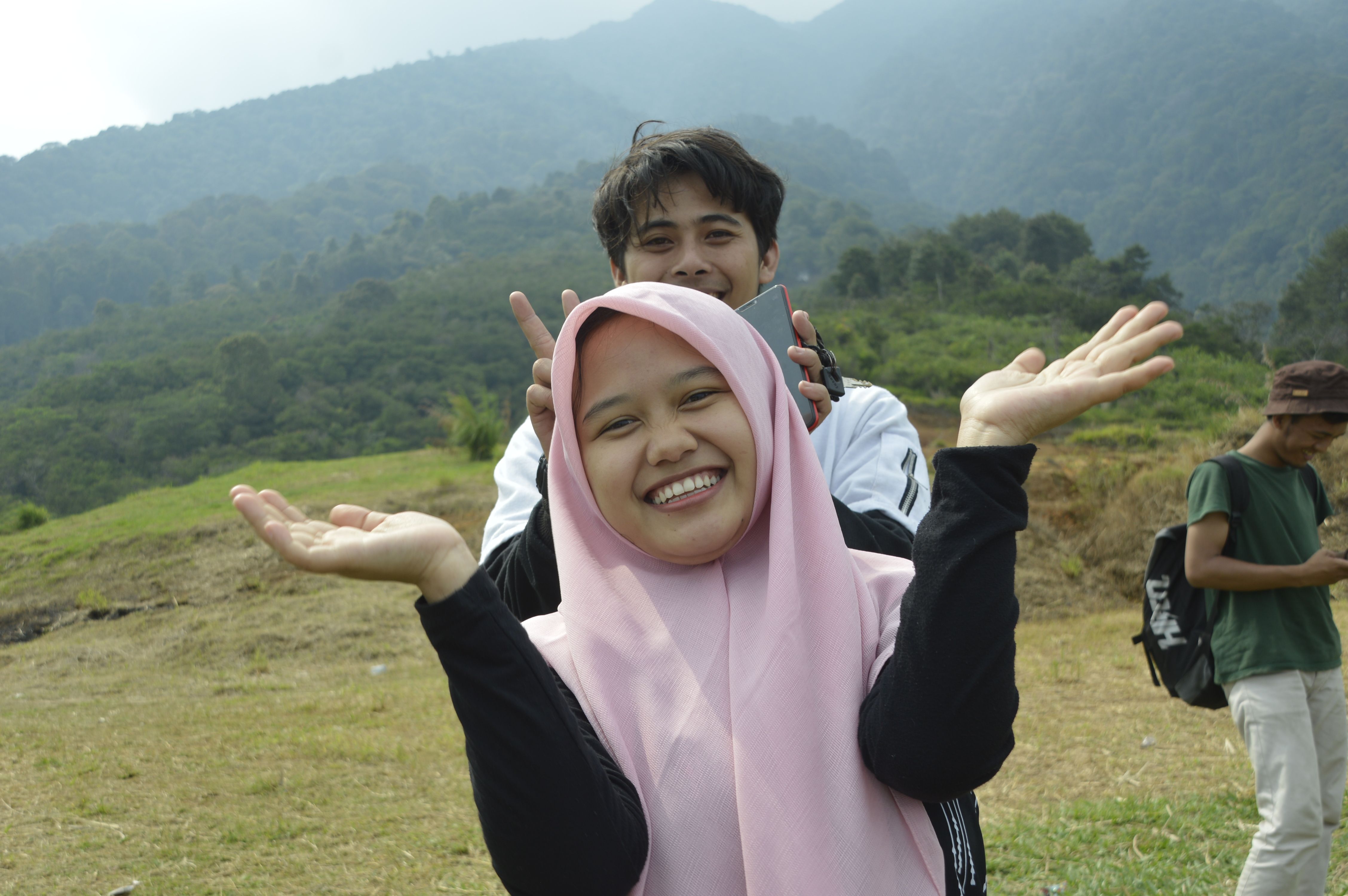 Smiling friends enjoying a sunny day in a lush mountain setting, creating joyful memories.
