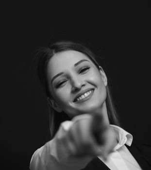 Black and white portrait of a smiling woman pointing with a confident expression.