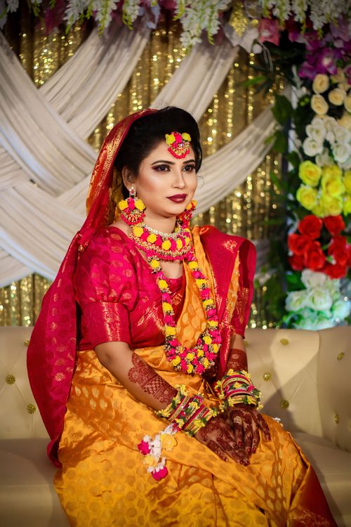 Free Beautiful Indian bride in traditional attire and floral jewelry sitting for a portrait. Stock Photo