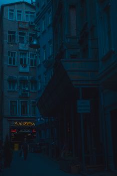 A dimly lit alleyway in a city at dusk with an opera sign, showcasing urban architecture.