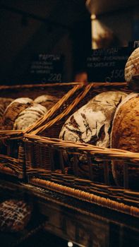 A selection of fresh artisan bread in wicker baskets at a cozy bakery counter.