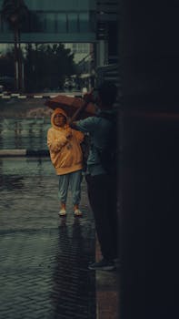 A moody urban scene in Dubai featuring people with umbrellas on a rainy day.