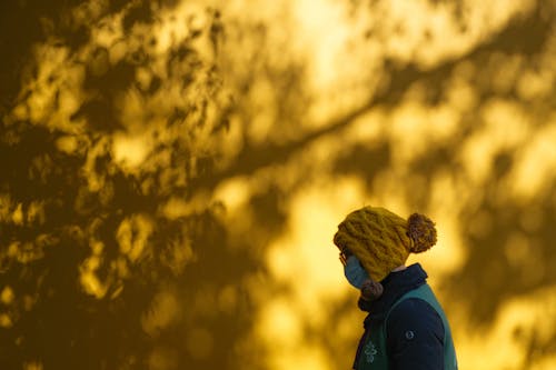 Photo of a Person Beside a Yellow Wall