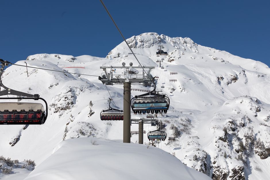 Breathtaking view of a ski lift on a snow-covered mountain under a clear blue sky.