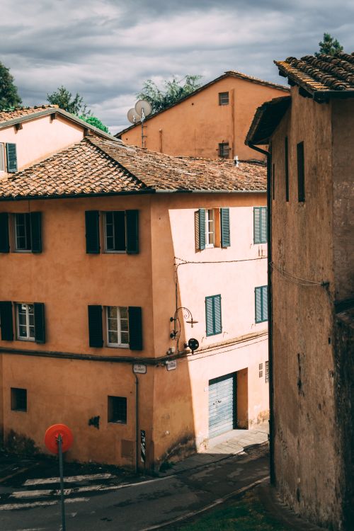 Free Sunlit buildings with shutters in Lucca, Tuscany, capturing Italian architecture and urban charm. Stock Photo