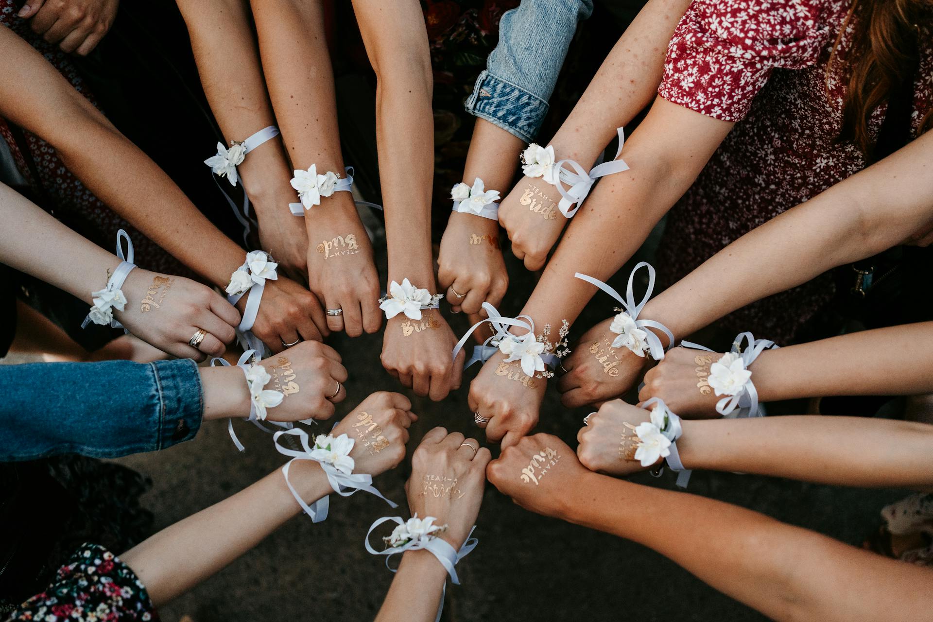 A group of women at a bachelorette party showing unity with matching 'Team Bride' bracelets in a circle.