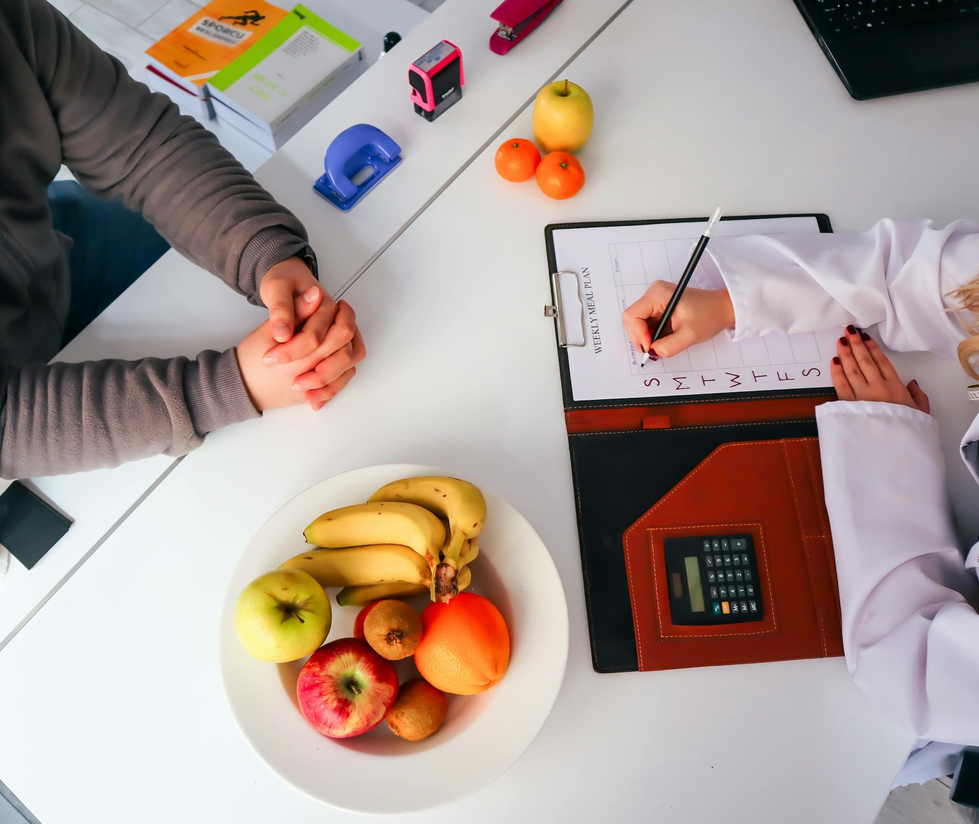 Top view of a dietitian planning a healthy diet with fresh fruits on the table, focusing on health and nutrition.