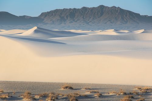 Free Breathtaking sand dunes at White Sands National Park with mountainous backdrop under blue sky. Stock Photo