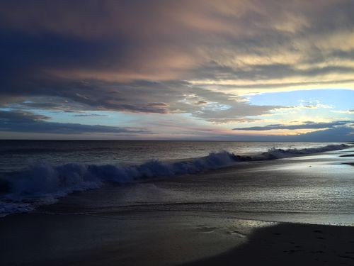 Free Capture of a scenic ocean shoreline at sunset, with dramatic waves and cloudy skies. Stock Photo