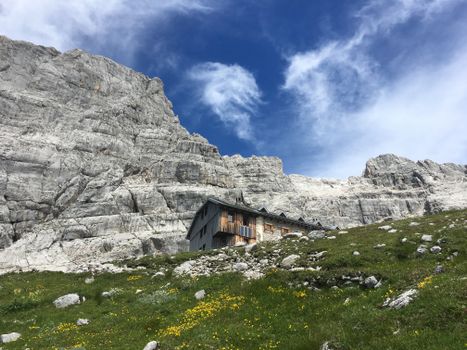 Picturesque mountain cottage nestled beneath rocky alpine cliffs in the Austrian Alps.