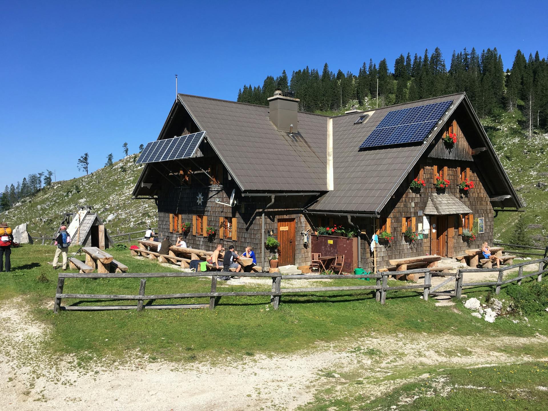 Charming wooden lodge in the countryside with solar panels under clear blue skies.