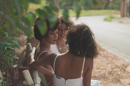 三个年轻女子坐在户外的长凳上，一起享受着阳光明媚的一天