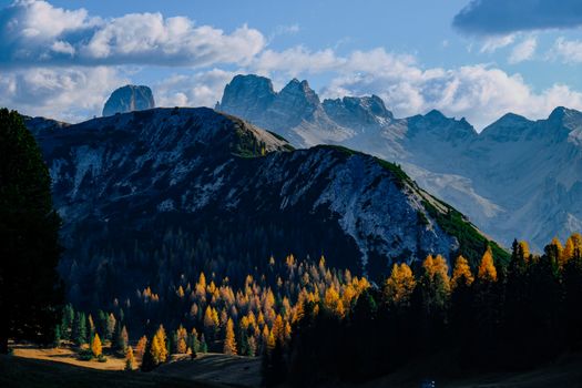 Breathtaking autumn landscape of the Dolomites mountains in Italy, showcasing vibrant trees and rocky peaks.