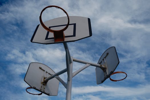 A trio of basketball hoops captured from below against a vibrant blue sky, highlighting outdoor sports.