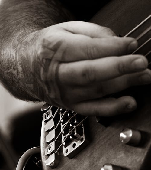A Hand Strumming Guitar in Black and White Photography