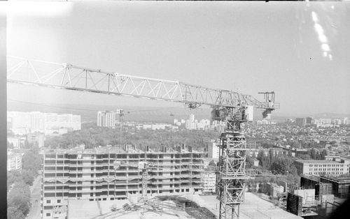 Free Aerial view of an urban construction site with a crane and cityscape in black and white. Stock Photo