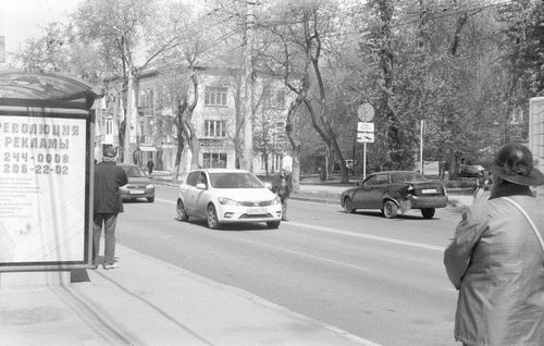 Free A monochrome view of a bustling city street featuring cars and pedestrians. Stock Photo