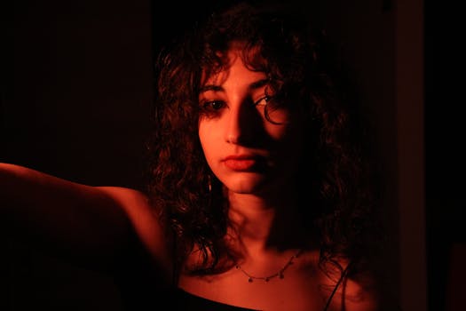 Portrait of a young woman with curly hair in artistic low lighting.