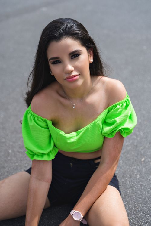Free Portrait of a stylish young woman in a vibrant green top seated outdoors. Stock Photo