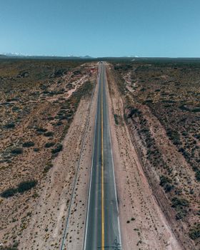 Drone shot of a straight highway through desert landscape in Neuquén, Argentina.