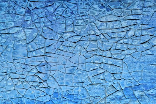 A detailed close-up of cracked blue paint creating an intricate texture pattern.
