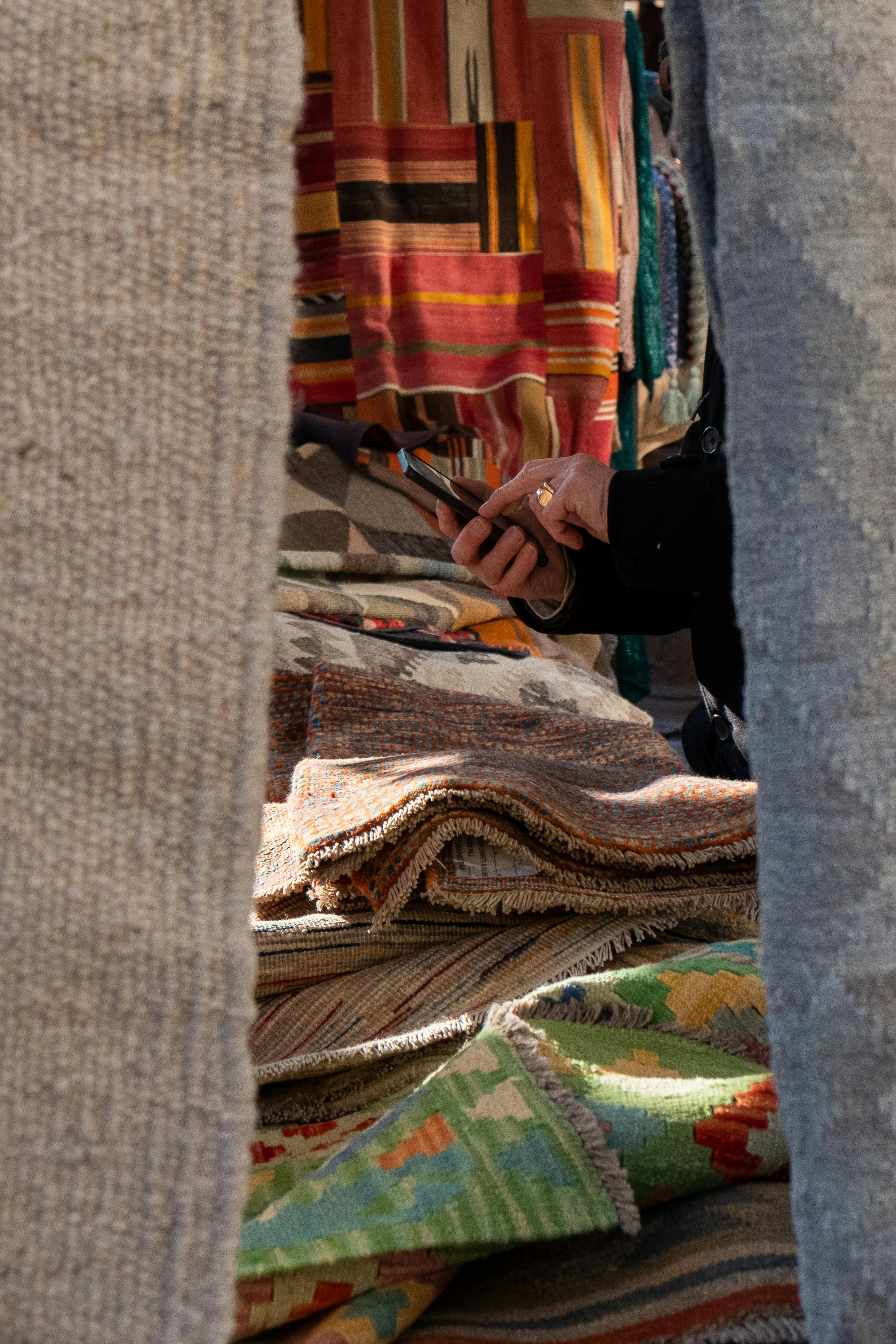 Hand examining vibrant textiles at a bustling market stall. Perfect blend of culture and shopping.