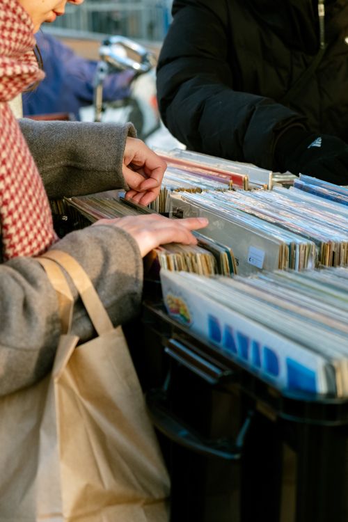 Free Close-up of hands browsing vinyl records at an outdoor market. Stock Photo