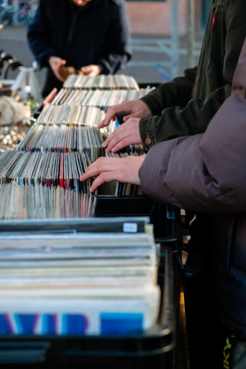 Free Hands of people browsing vinyl records at an outdoor market stall. Stock Photo